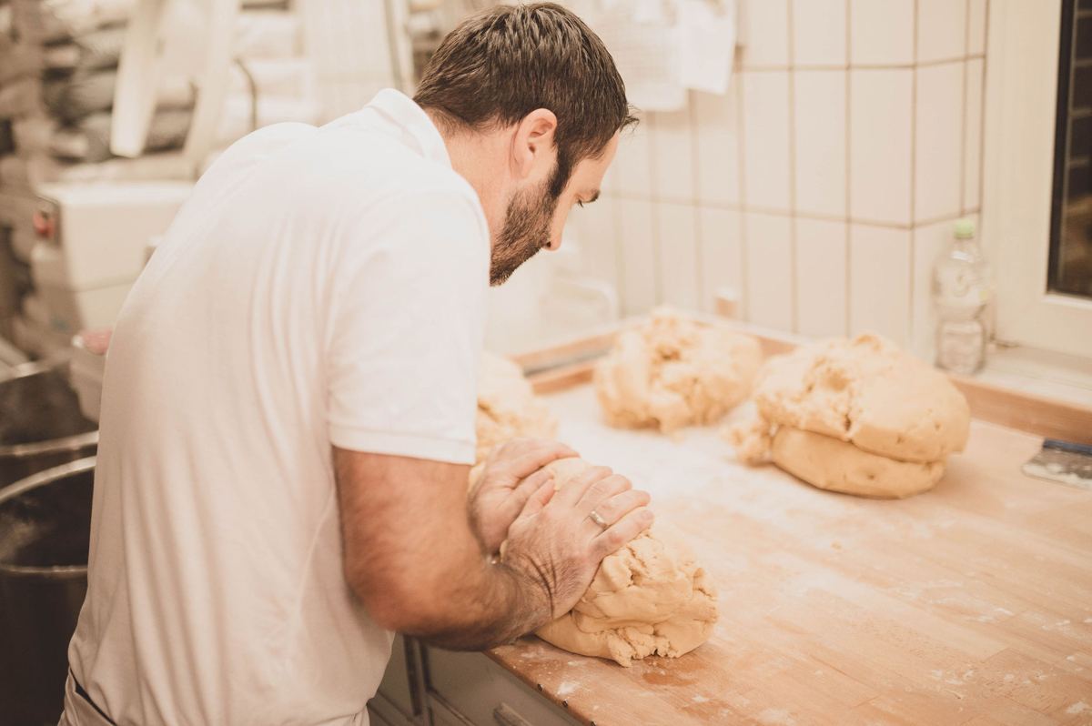 Bäcker knetet Brotteig auf dem Backtisch