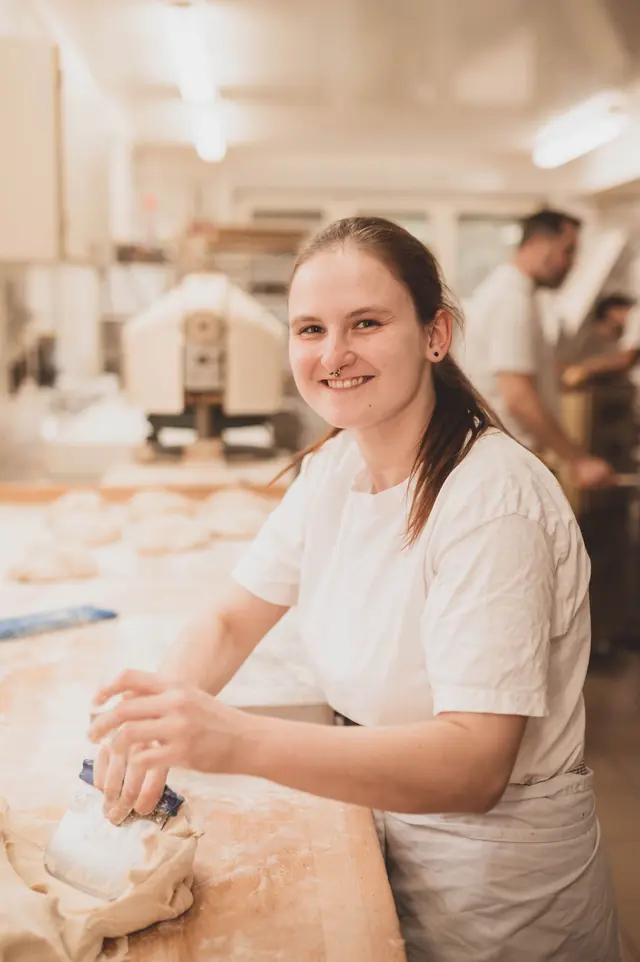 Bäckerin lächelt bei der Arbeit am Teig