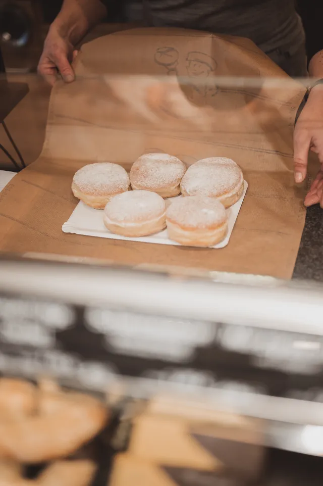 Berliner werden an der Theke in Papier verpackt