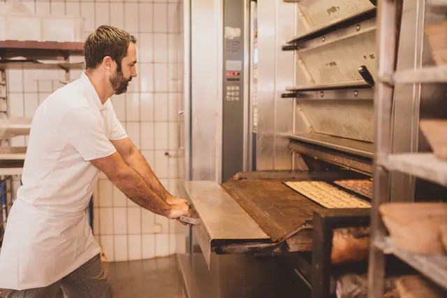 Bäcker schiebt ein Blech in den Backofen