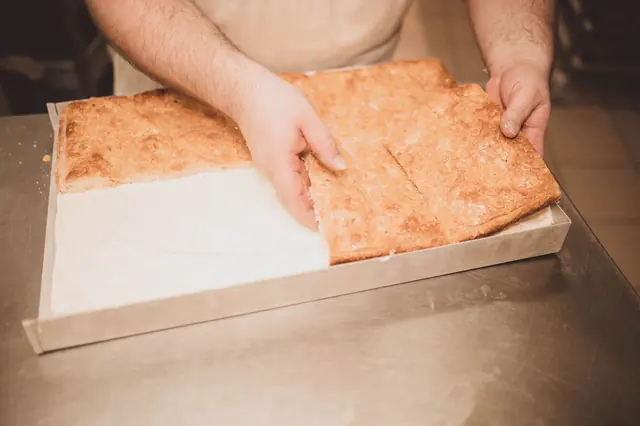 Frisch gebackener Blechkuchen wird aus der Form gehoben