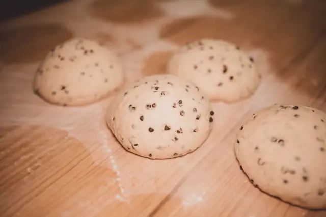 Frisch geformte Brötchen mit Rosinen auf dem Backbrett