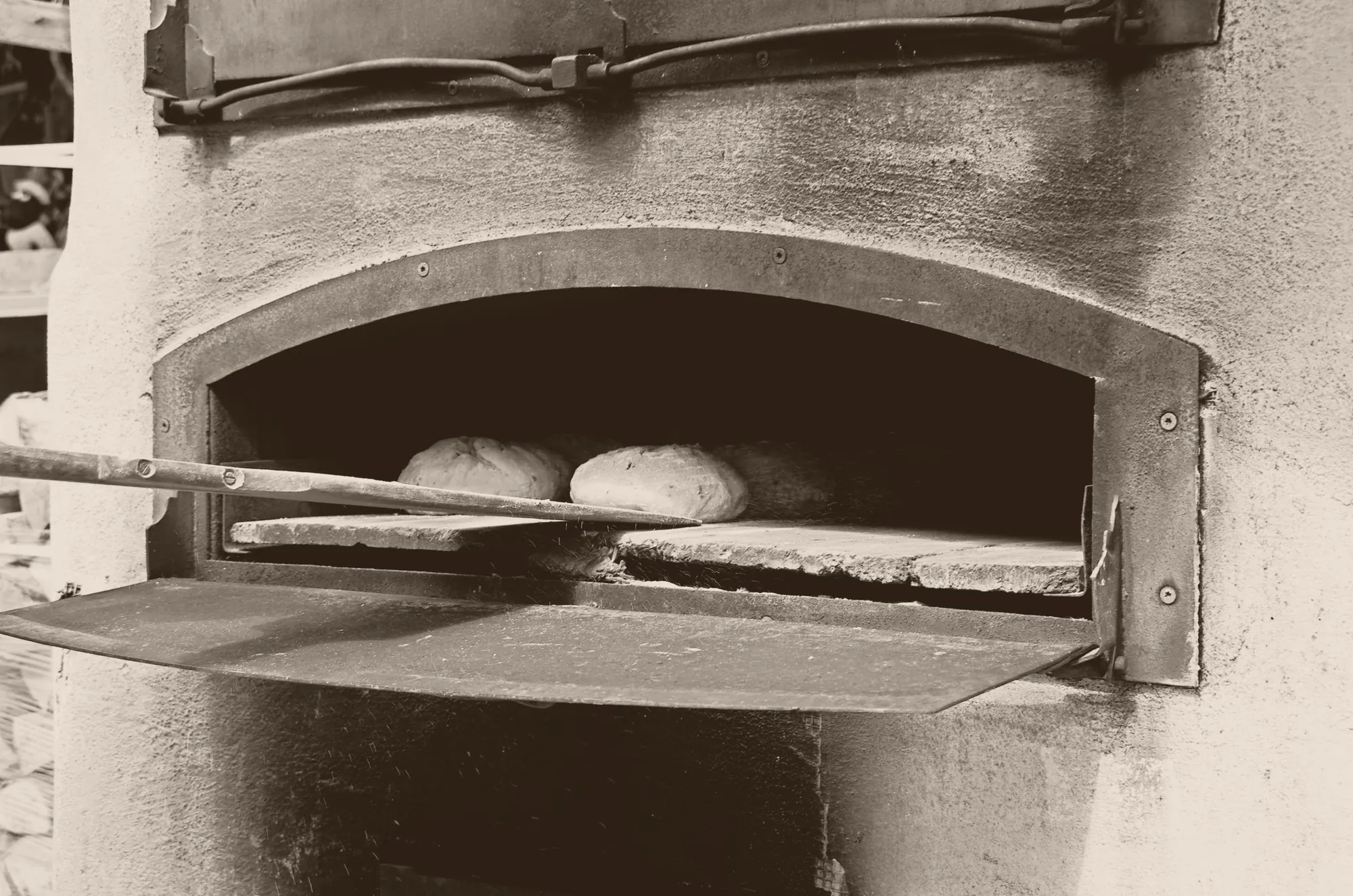 Zwei Brote auf dem Backschieber im gemauerten Ofen, Sepia-Aufnahme