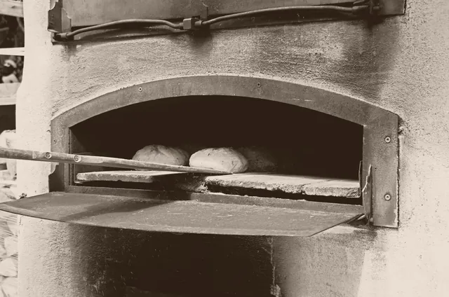Zwei Brote auf dem Backschieber im gemauerten Ofen, Sepia-Aufnahme