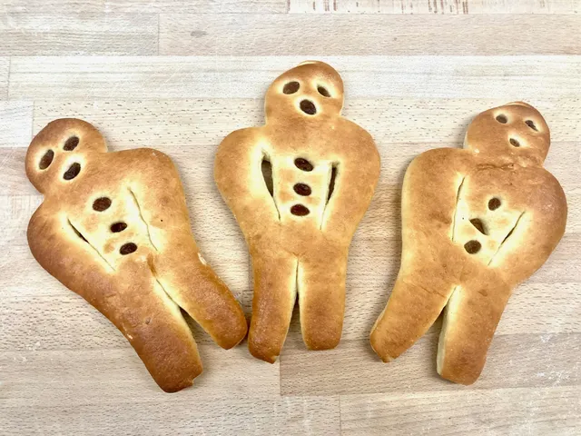 Drei Hefeteig-Männchen auf einem Holzbrett